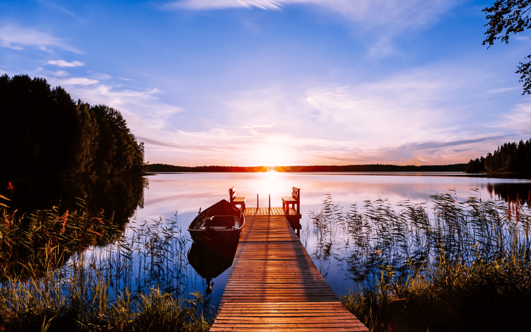 Wooden dock with boat at sunset over calm lake in Detroit Lakes, MN