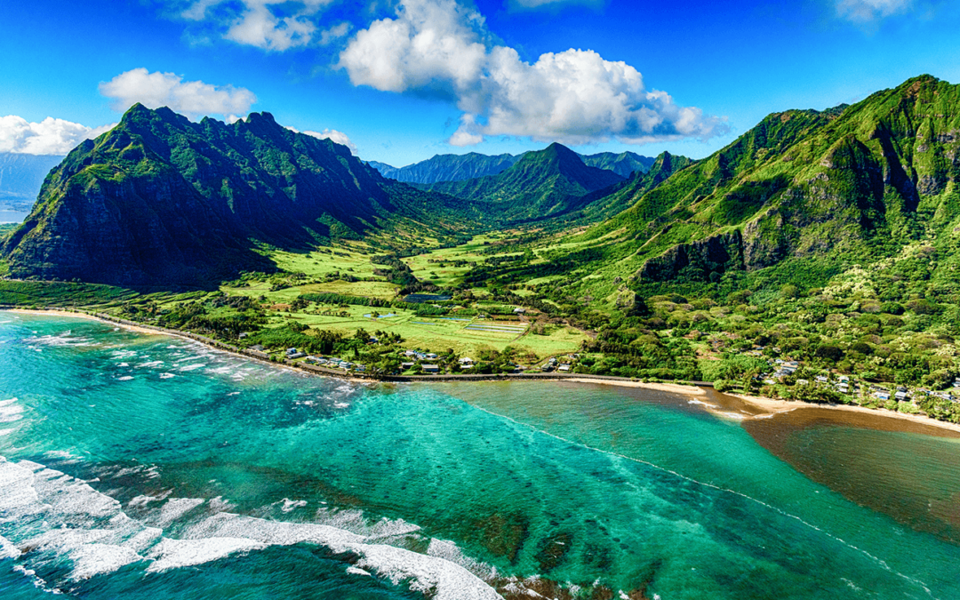 Aerial view of a lush green valley and mountains on the Hawaiian coast.