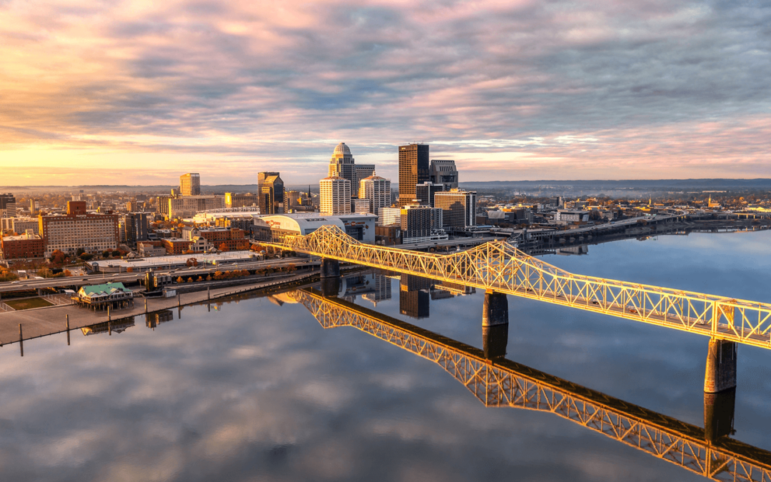 Louisville skyline and bridge reflecting on the Ohio River at sunrise.