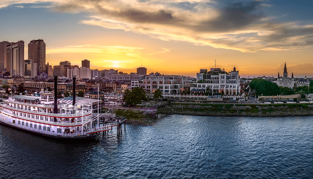 New Orleans riverboat docked along the Mississippi River at sunset.