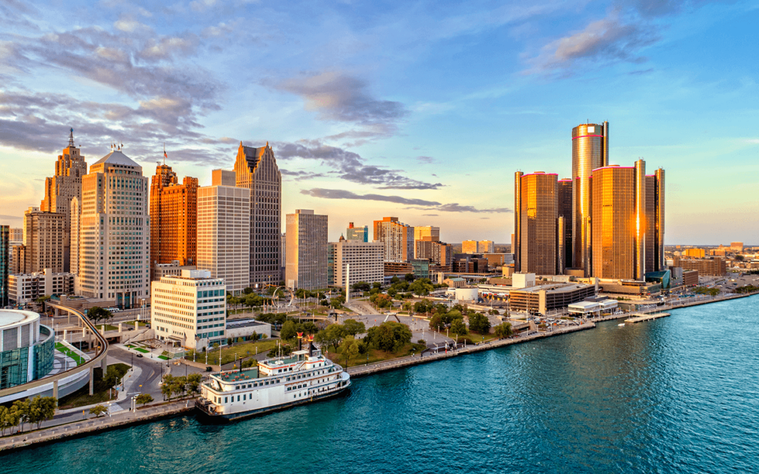 Detroit skyline at sunset with Renaissance Center and riverfront view.