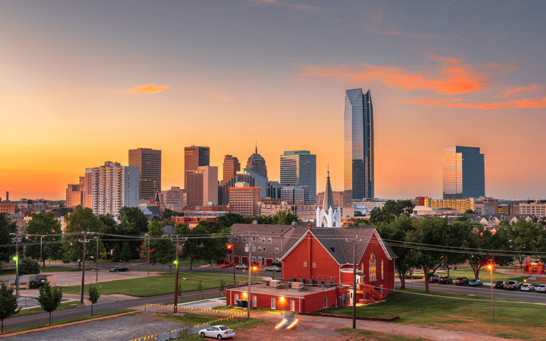 Oklahoma City skyline at sunset with a red brick church in the foreground.