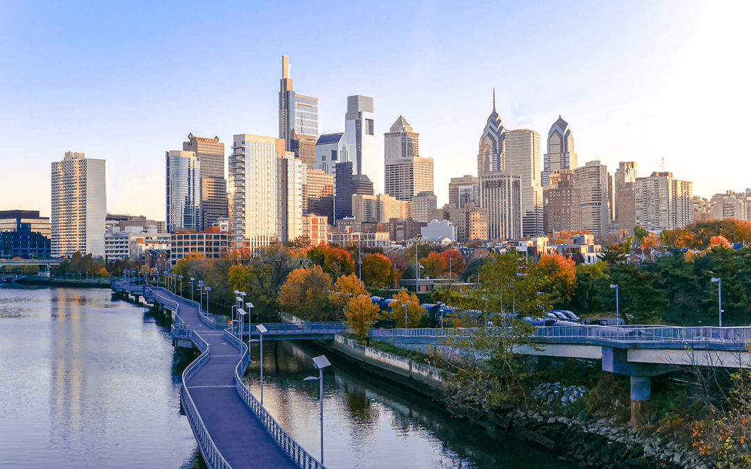 Philadelphia city skyline with a waterfront pathway at sunset.