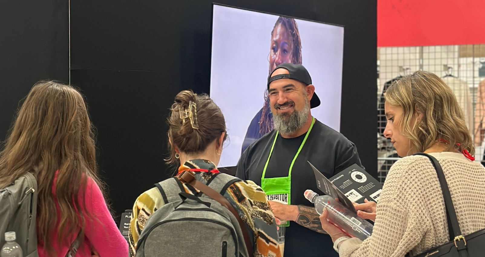 A real estate professional speaking with three attendees at a conference booth, illustrating how overcoming call reluctance leads to stronger client engagement.